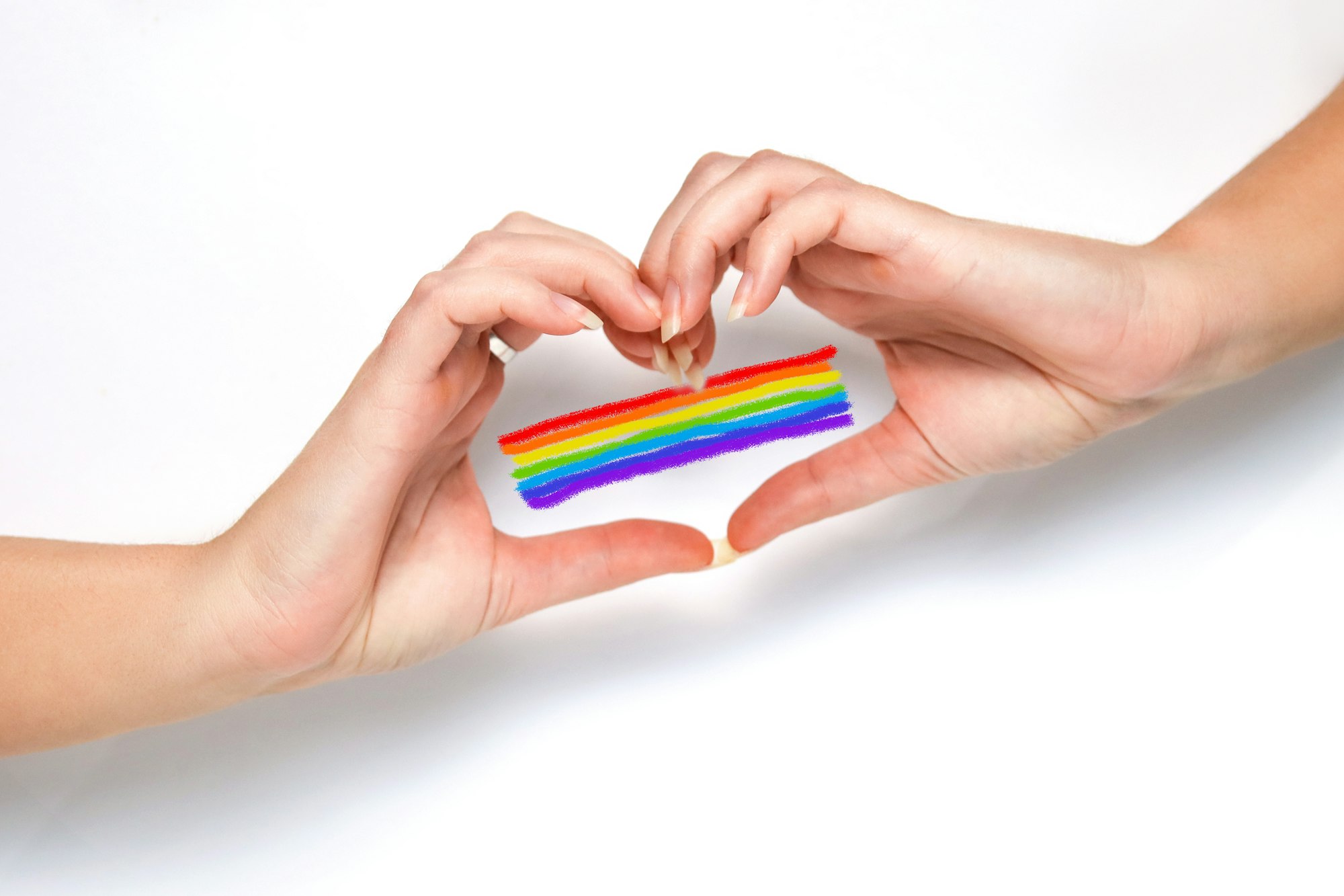 Hand with rainbow heart, LGBTQ rights, pride month. White background. Woman hands making a heart ges